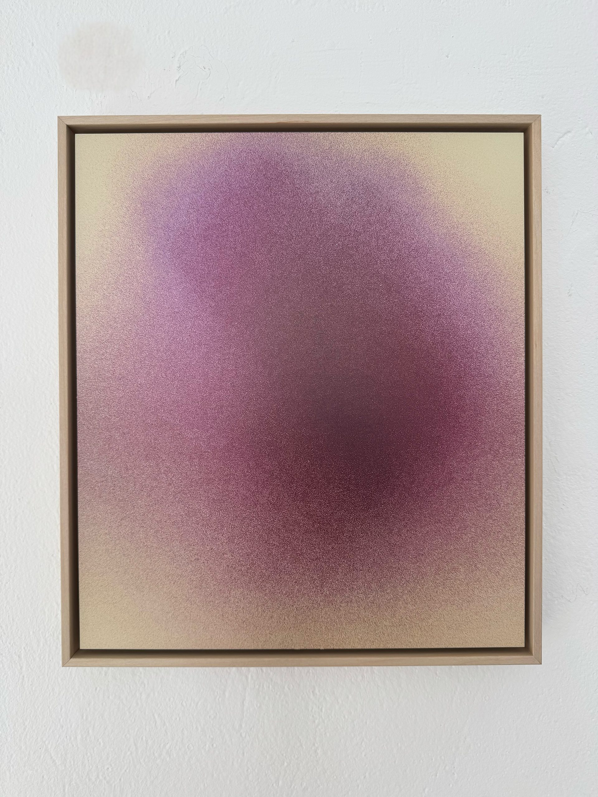 Ein gerahmtes abstraktes Kunstwerk zeigt einen dunstigen Farbverlauf aus lila, rosa und gelben Tönen, der in der Mitte eine weiche, wolkenartige Form vor einem hellen Hintergrund bildet. Der Rahmen ist einfach und aus Holz.