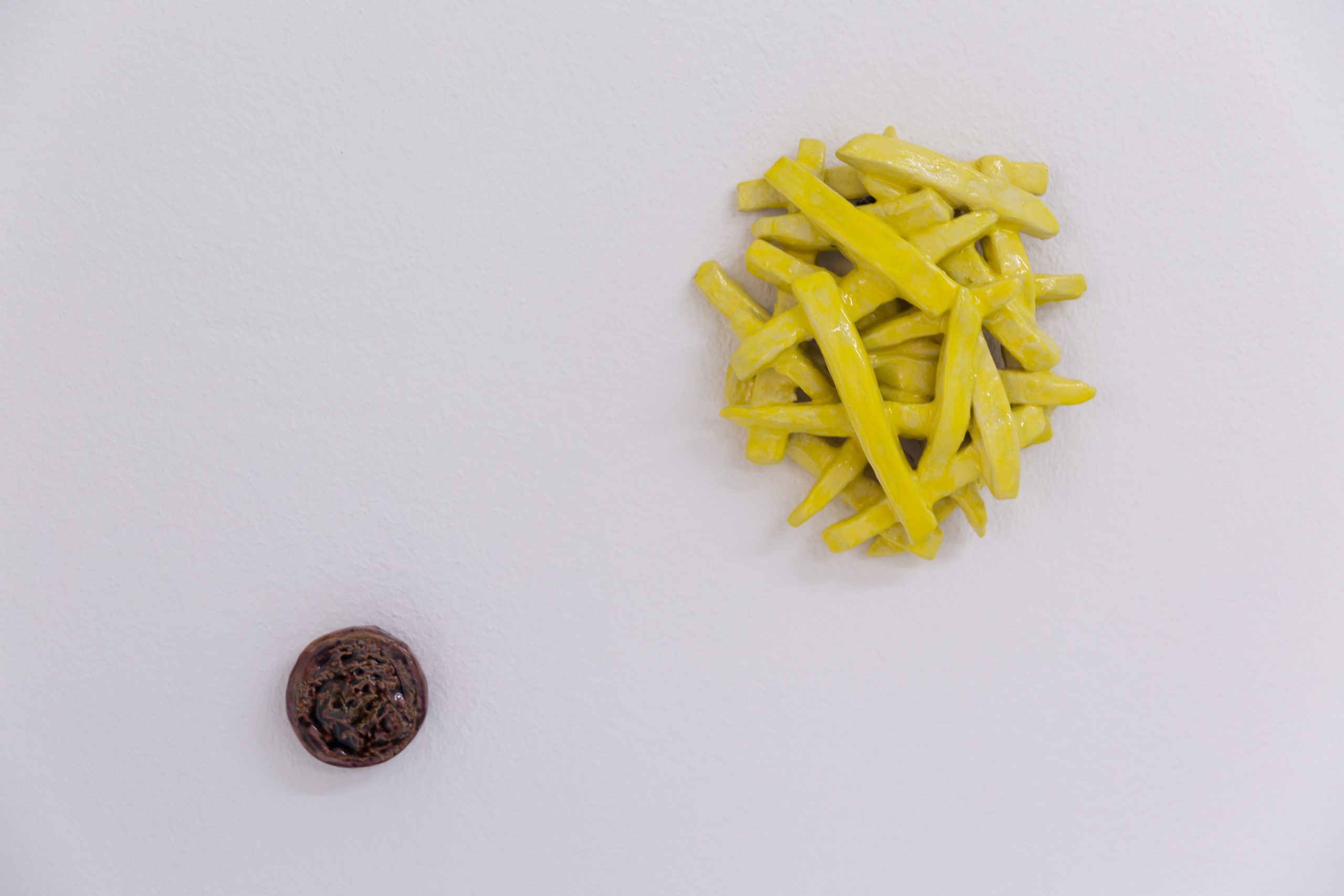 Ein kleiner Haufen gelber Wachsbohnen und ein einzelner dunkelbrauner Pilz auf einer schlichten weißen Fläche.