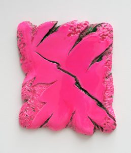 Eine abstrakte Skulptur in quadratischer Form mit rauer Textur, bemalt in leuchtendem, glänzendem Rosa mit tiefen, gezackten Rissen, die sich durch die Oberfläche ziehen, montiert auf einem weißen Hintergrund.