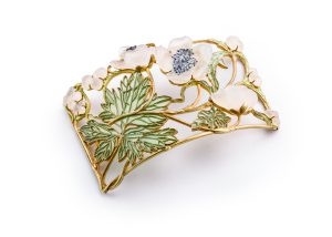 Ein dekoratives Goldarmband mit verschlungenen grünen Blättern und weißen Blumen mit zarten Details auf weißem Hintergrund.