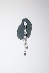 Eine minimalistische Wandskulptur mit abstrakten weißen und grauen Formen mit schwarzen Umrissen, montiert auf einer schlichten weißen Wand. Die Skulptur wirft weiche Schatten und erzeugt einen mehrschichtigen und dimensionalen Effekt.