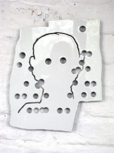 Eine glänzende weiße Keramikfliese mit Löchern und Ausschnitten, die den Umriss eines menschlichen Kopfes und Schultern bilden, montiert auf einer weißen Ziegelwand.