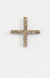 Ein Pluszeichen aus gesprenkeltem beigem und braunem Stein steht mittig auf einem schlichten weißen Hintergrund.