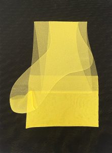 Ein Stück durchsichtiger gelber Stoff wird kunstvoll auf einer dunklen, strukturierten Oberfläche gefaltet, wodurch geschichtete und durchscheinende geometrische Formen entstehen.