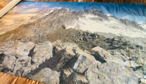 Ein großes Vinyl-Banner mit einer Panoramaaufnahme einer felsigen, schneebedeckten Bergkette.